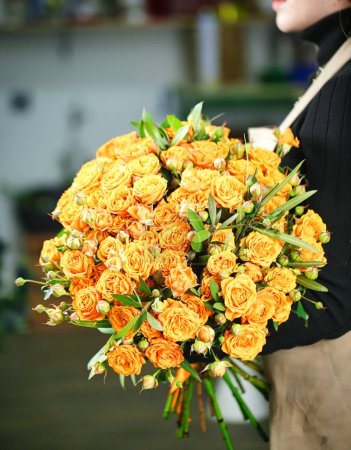 A woman gracefully holds a bouquet of vibrant yellow roses, with plenty of copy space.