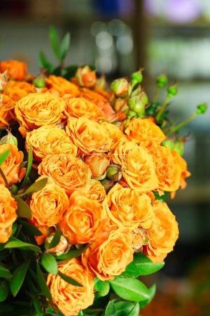 A stunning bouquet of orange roses arranged on top of a table, with ample copy space available.