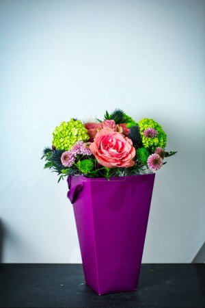 A vibrant purple vase filled with an assortment of beautiful flowers sits atop a table, providing a visually appealing centerpiece.