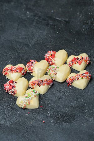 Téléchargez les photos : Un tas de biscuits en forme de cœur, décorés avec des aspersions, créant un affichage vibrant et délicieux. - en image libre de droit