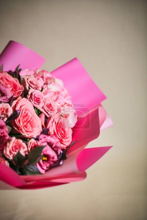 A beautiful bouquet of pink roses wrapped in pink paper, with plenty of copy space.
