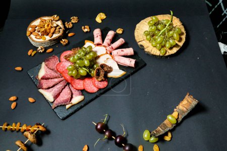Photo for A platter filled with a variety of meats, cheeses, grapes, and nuts displayed enticingly. - Royalty Free Image