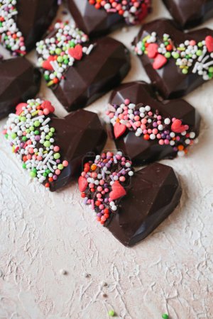 Téléchargez les photos : Un plateau rempli de chocolats en forme de cœur, chacun généreusement enrobé d'une variété d'aspersions vibrantes. - en image libre de droit