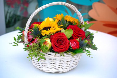 Ein lebendiges Arrangement von Blumen in einem Korb sitzt auf einem Tisch und sorgt für einen Farbtupfer und Schönheit.