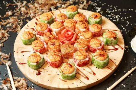 A wooden plate is filled with a variety of sushi rolls featuring fresh fish, rice, and vegetables, expertly prepared and presented.