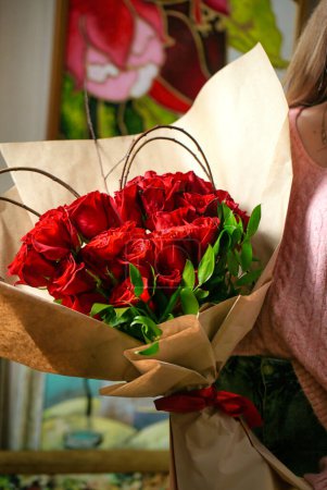 Eine Frau hält einen schönen Strauß roter Rosen mit Kopierraum in der Hand.