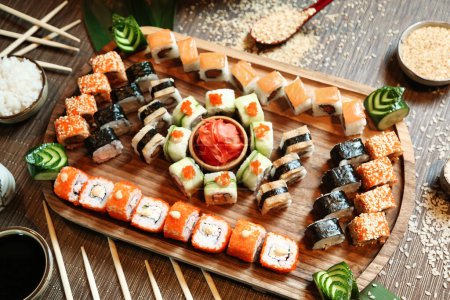 A wooden tray displays a variety of sushi rolls paired with chopsticks.