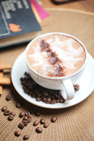 Un cappuccino est assis sur une soucoupe, avec un arrangement de grains de café qui l'entourent.