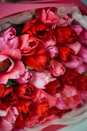 Un arrangement vibrant de fleurs roses et rouges magnifiquement affichées dans une boîte rose, avec amplement d'espace de copie.