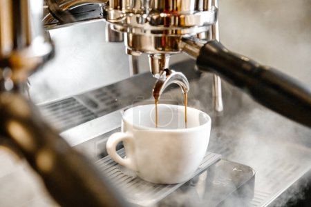 A close-up photo of a person pouring a cup of coffee into the coffee machine, preparing for a fresh brew.