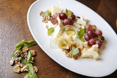 Un plato blanco tiene un generoso arreglo de uvas y queso.