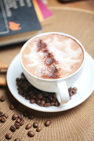 Téléchargez les photos : Un cappuccino aromatique sur une petite soucoupe entourée d'un anneau de grains de café, créant une composition de café visuellement agréable. - en image libre de droit