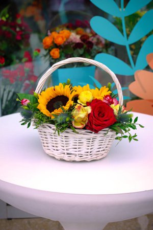 A vibrant basket of flowers sitting on top of a table, providing a beautiful centerpiece for any occasion or setting.