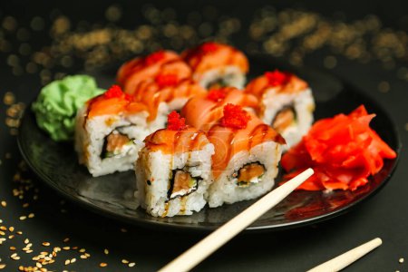 Téléchargez les photos : Une assiette noire avec une sélection de sushis servis avec des baguettes. - en image libre de droit