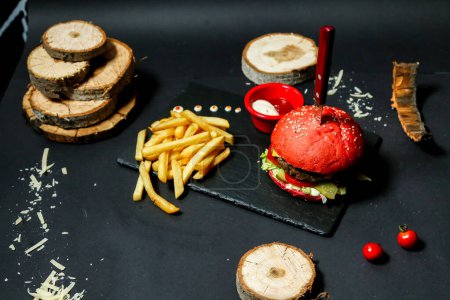 Téléchargez les photos : Un hamburger appétissant et des frites croustillantes sont présentés sur une planche à découper en bois. - en image libre de droit