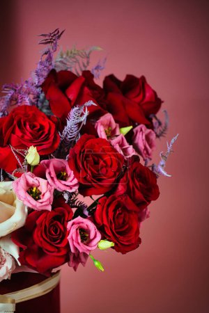 Ein lebendiger Strauß roter und pinkfarbener Blumen, arrangiert in einer Vase, mit viel Kopierraum.