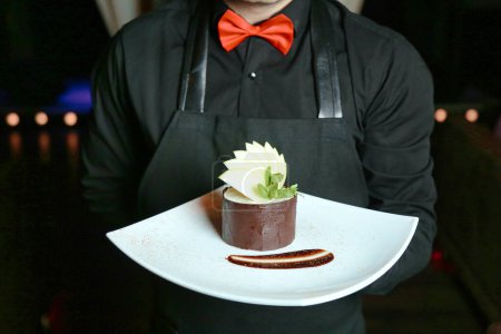 A man holds a plate with a delicious dessert on it.
