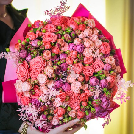 Téléchargez les photos : Une femme tient un arrangement magnifique de fleurs, créant une scène vibrante et belle. - en image libre de droit
