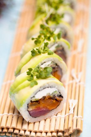 Téléchargez les photos : Une vue détaillée d'un rouleau de sushi placé sur un tapis de bambou. - en image libre de droit