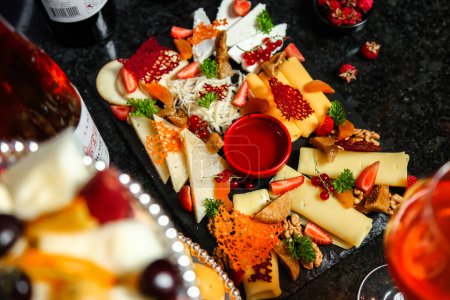 A platter showcasing a variety of cheeses and fresh fruits, accompanied by a glass of wine.