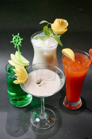 Une table présentant trois types distincts de boissons un soda rafraîchissant, un cappuccino mousseux et un verre réfrigéré de jus de fruits.