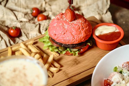 Una hamburguesa con queso y un bollo en forma de corazón, servido con un lado de papas fritas crujientes.