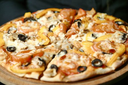 Téléchargez les photos : Une délicieuse pizza garnie de divers ingrédients se trouve sur une assiette en bois rustique. - en image libre de droit