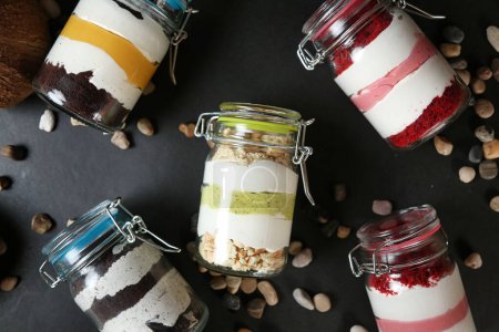 Vier transparente Gläser gefüllt mit einer Vielzahl köstlicher Desserts, die eine köstliche Auswahl an süßen Leckereien präsentieren.