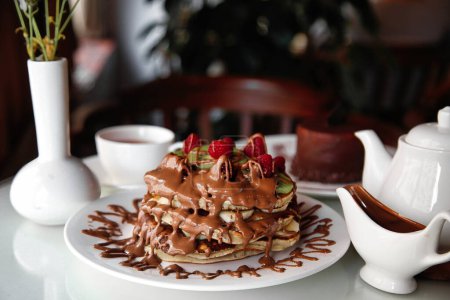 A white plate showcases a decadent dessert covered in rich chocolate.