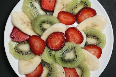 Photo for A white plate showcases perfectly sliced kiwi and juicy strawberries in a mouthwatering arrangement. - Royalty Free Image