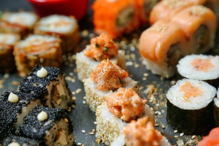 A detailed view of a plate filled with a variety of meticulously prepared sushi rolls.
