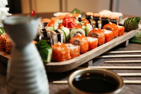 Téléchargez les photos : Un plateau rempli de différents types de sushis soigneusement disposés sur une table, accompagnés d'une paire de baguettes. - en image libre de droit