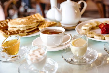 Foto de Una mesa está llena de platos de comida y tazas de té, creando un ambiente encantador para una comida. - Imagen libre de derechos