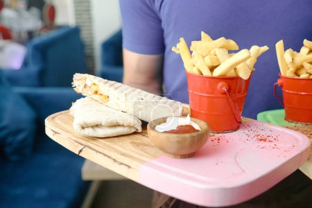 Eine Person hält ein Tablett mit einem leckeren Sandwich und einer Portion knuspriger Pommes.