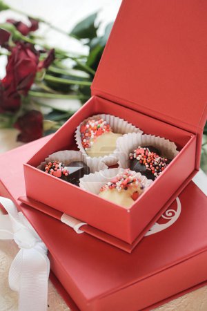 Ein paar rote Schachteln gefüllt mit leckeren Cupcakes stehen zum Verkauf auf einer Arbeitsplatte.