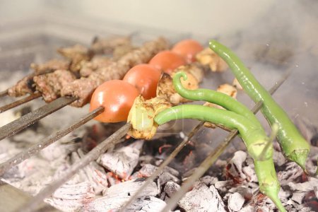 A variety of foods, including meat, vegetables, and seafood, are being grilled on an outdoor grill.