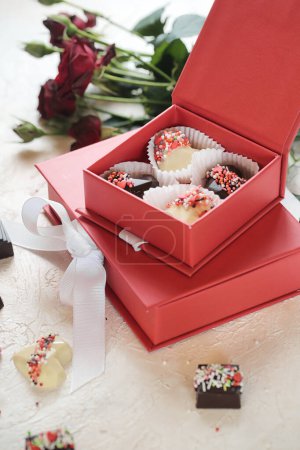 A couple of red boxes filled with chocolates sit on top of a table.