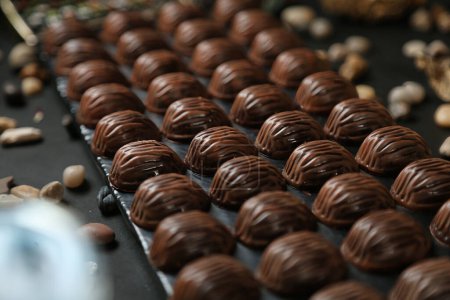 Téléchargez les photos : Plusieurs chocolats sont disposés de manière soignée et ordonnée tout en se déplaçant sur une bande transporteuse mécanique. - en image libre de droit