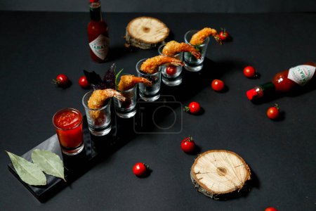 A black table adorned with glasses filled with an assortment of appetizing food.