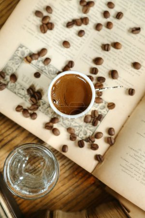 Una imagen mostrando una taza de café descansando encima de un libro abierto.