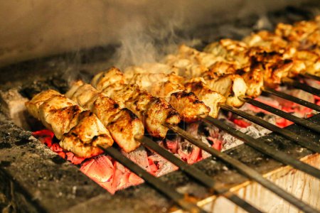 A close-up view of various types of food cooking on a hot grill, generating sizzling sounds and emitting aromatic smoke.