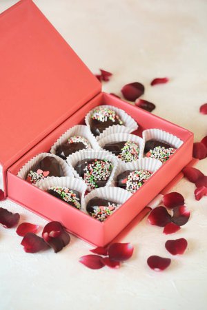 A box filled with delectable chocolates, adorned with colorful sprinkles, placed on a table.