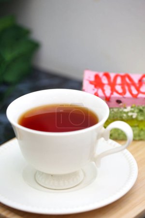 Eine Tasse Tee wird behutsam auf einen stabilen Holztisch gelegt und schafft eine einfache, aber einladende Szene.
