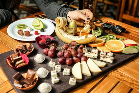 Photo for A tray holding a variety of cheeses, fresh fruit, and crisp crackers is displayed on a table. - Royalty Free Image