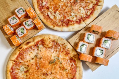 Une photo montrant une planche à découper avec une pizza, des sushis et des baguettes affichées.