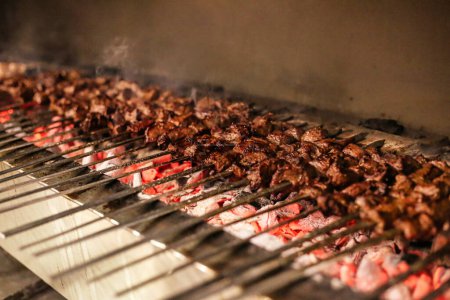 A grill with various cuts of meat sizzling and cooking to perfection on an outdoor barbecue.