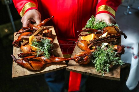 Photo for A person wearing a red shirt holds two trays of food. - Royalty Free Image