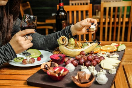 Téléchargez les photos : Une femme est assise à une table, dégustant un repas avec une assiette de nourriture et un verre de vin. - en image libre de droit