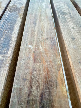 Detailed view of a wooden bench showing signs of rust and decay on its surface.