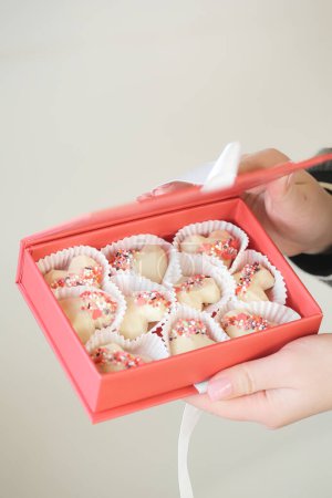 Téléchargez les photos : Une personne tenant une boîte remplie de biscuits en forme de coeur. - en image libre de droit